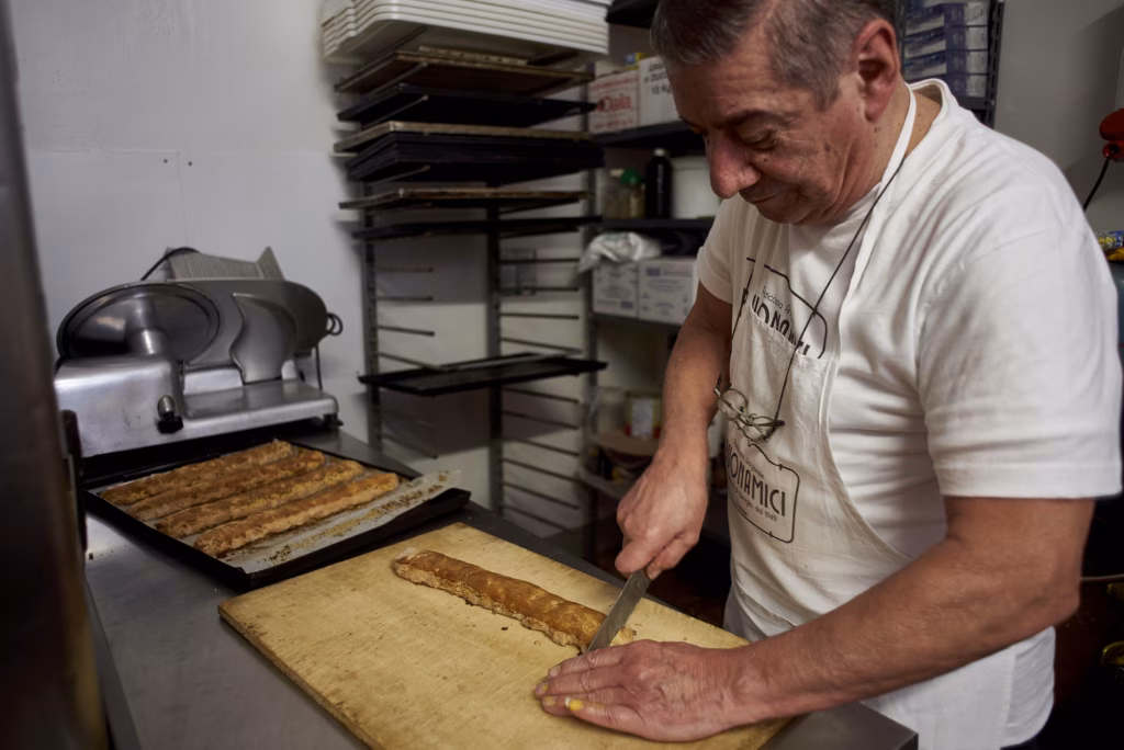 A biscotti baker cuts a fresh slice in Florence