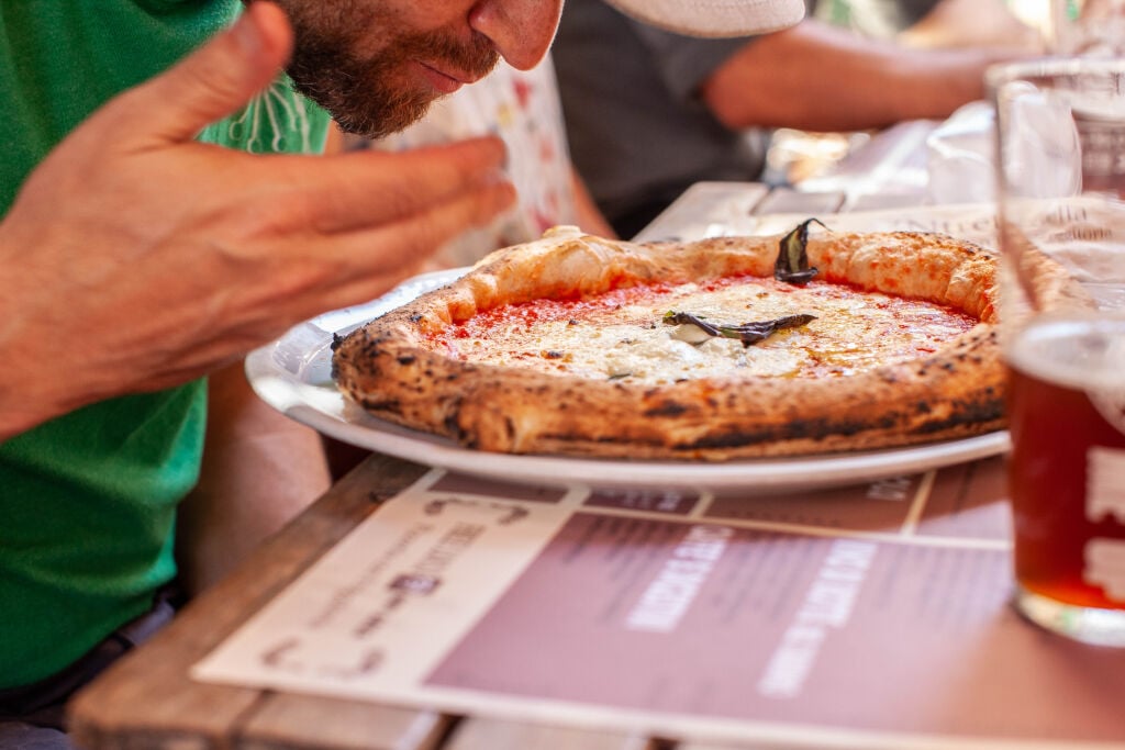 a man smells a neapolitan pizza on a naples food tour